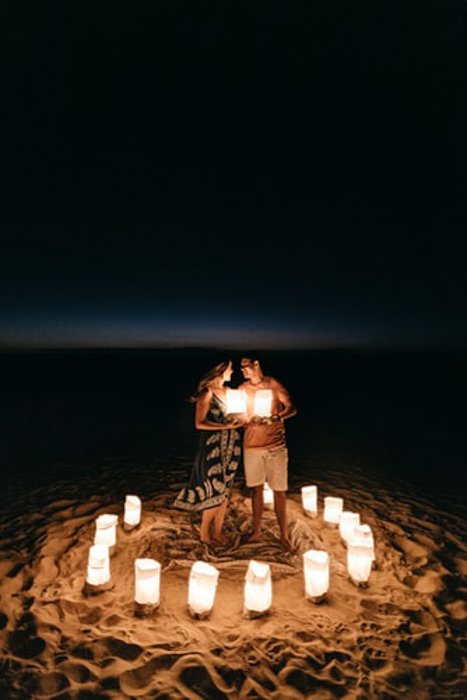 happy couple standing on the beach, surrounded by lanterns
