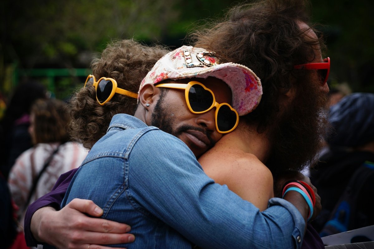 A man with heart sunglasses hugging another person from behind as a candid Valentines photoshoot idea