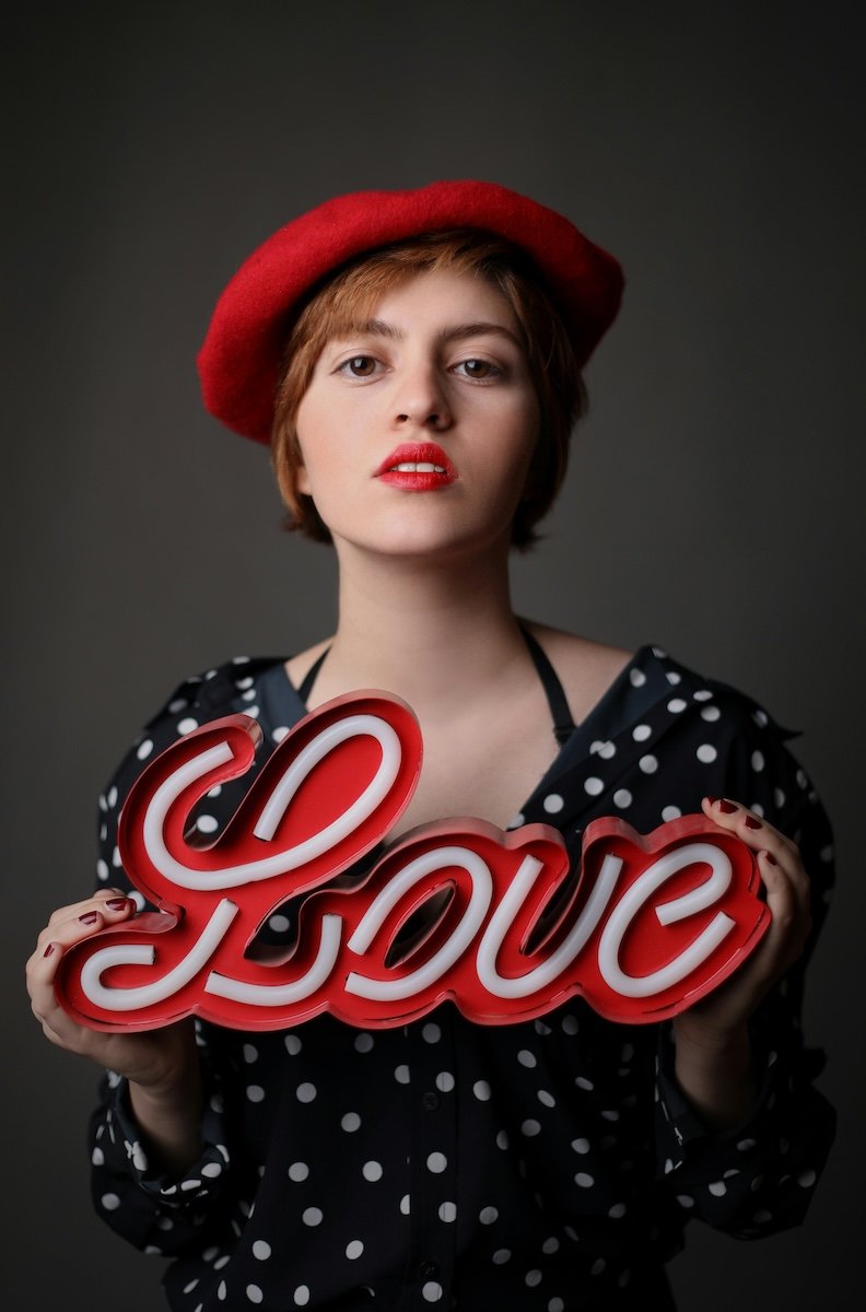 Woman in a red beret holding a love sign as a Valentines day photoshoot idea