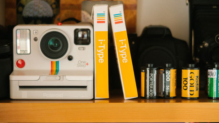 An image of a Polaroid instant camera and instant films besides 35m film rollsm film rolls