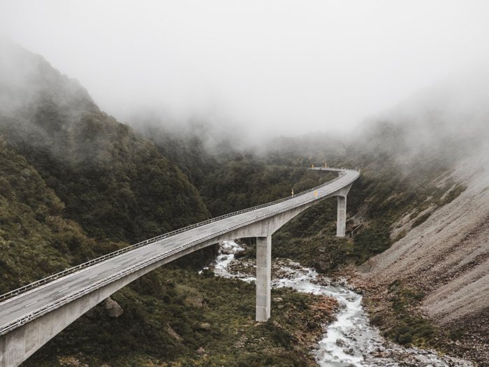 a photo of a road through mountains and fog show how to use leading lines photography