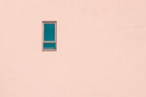 minimalist photography of a small window on a pink building facade