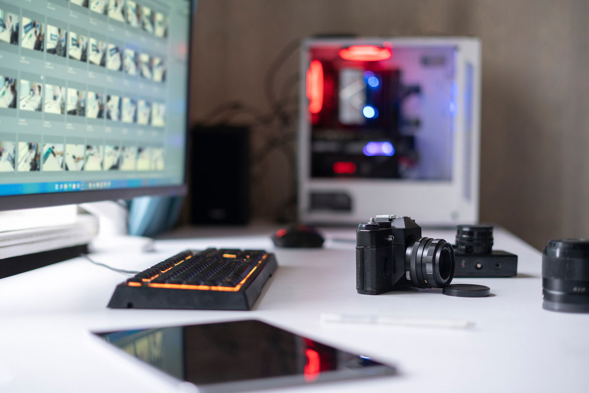 Photographer's workplace table with retro style camera and desktop computer with photo editing software