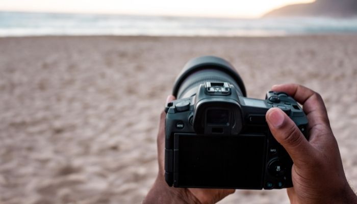 person holding dslr camera on the beach