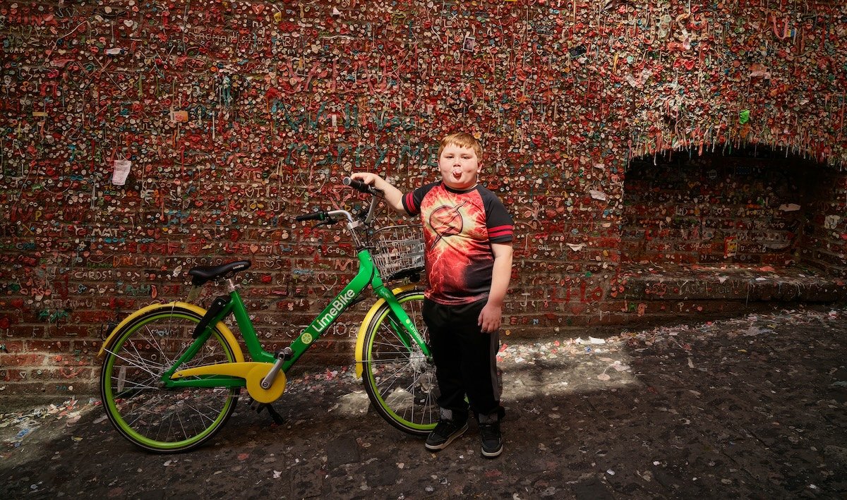A boy with a bike blowing a bubble against a textured wall to illustrate visual weight