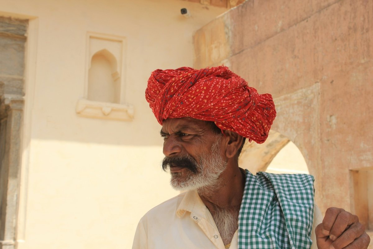 A street portrait of a man in a red turban looking off to the side showing visual weight