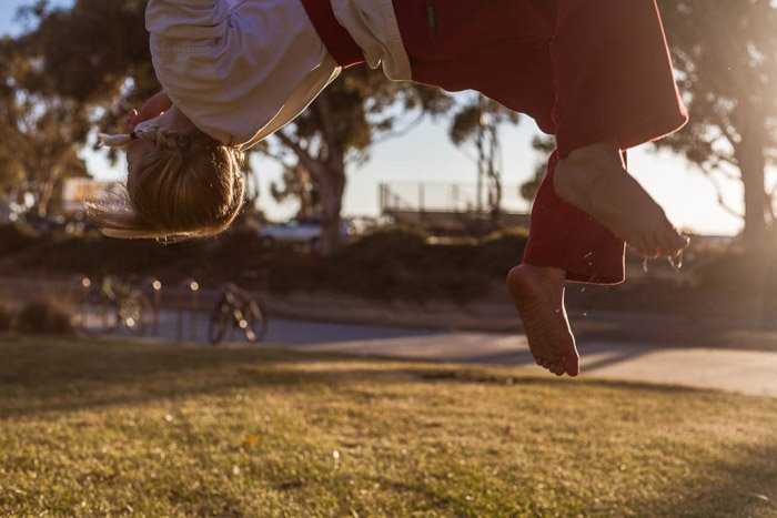 Candid child photo of a girl doing a backflip wearing martial arts clothing