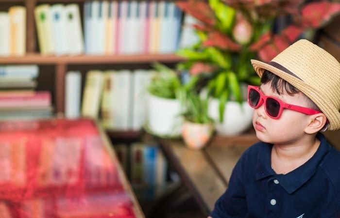 candid child photography of a little boy wearing a summery hat and sunglasses