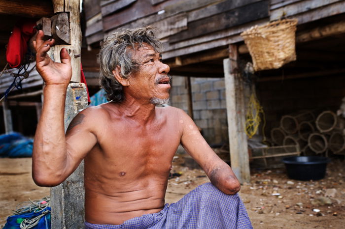 An environmental portrait photography shot of a Moken sea gypsie man in south Thailand telling us the story of how he lost his hand. 