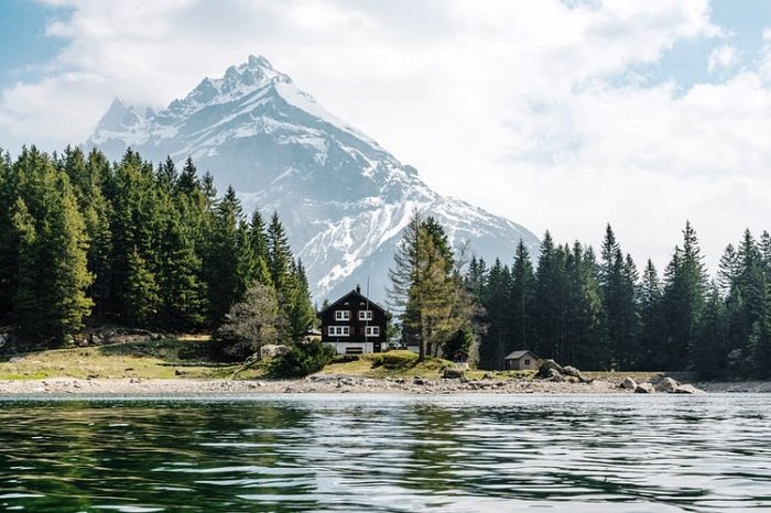 image of a house by a body of water with a mountain peak in the background