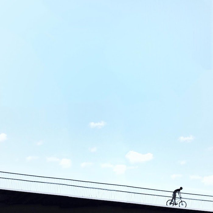 A minimalist photo of a cyclist on bridge