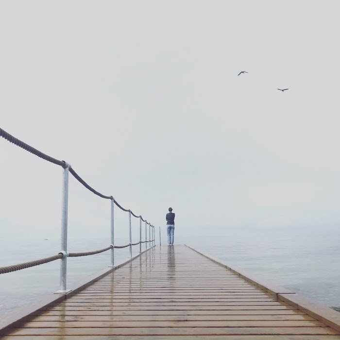 Minimalist photography: A minimalist image of a person standing on the end of a pier