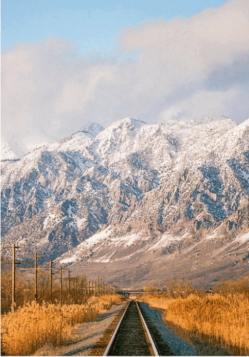 beautiful image of a train track leading to a snowy mountain range taken by one of our list's top film photographers