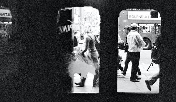 photograph of a busy street taken through the view of glass shop doors