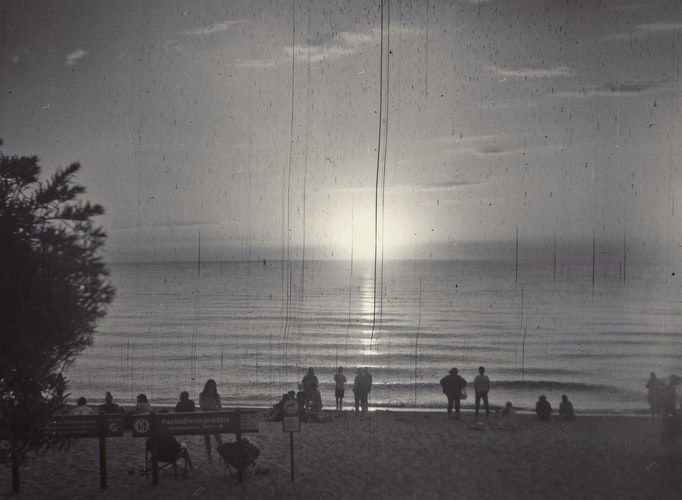 black and white photograph of the sun setting on a beach