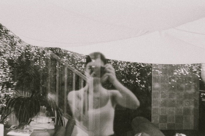 black and white films photograph of a window view with the photographer's reflection also showing