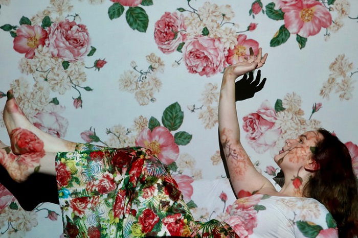 Studio image of a woman falling with a floral skirt, background, and projection for editorial style photography