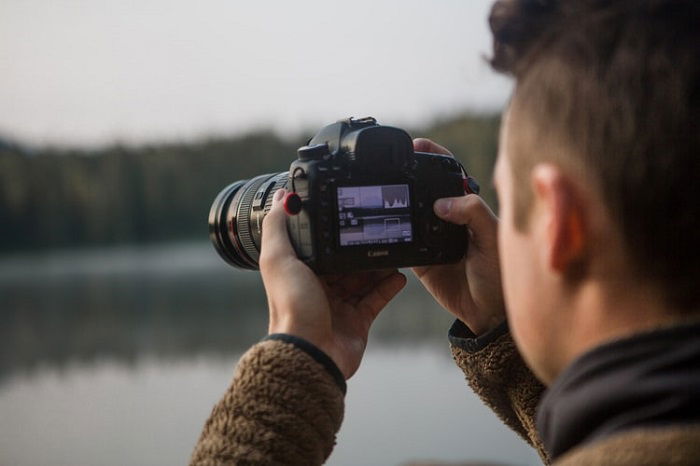 fotógrafo tirando uma foto com um lago desfocado ao fundo