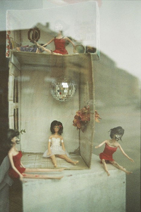 photograph of a small dollhouse shot on expired film, with a grey hue and film grain