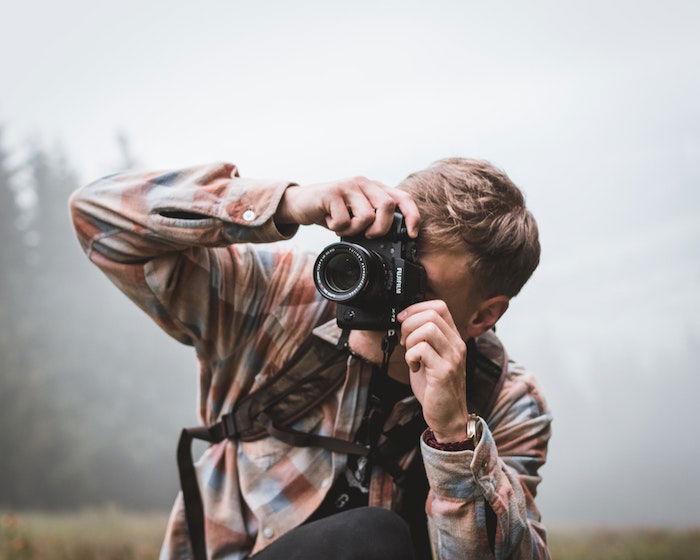 A man talking a photo with Fujifilm camera and lens outside