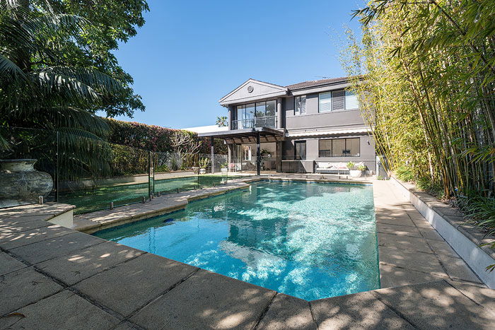 A swimming pool in the foreground of a large house shot by a real estate photographer