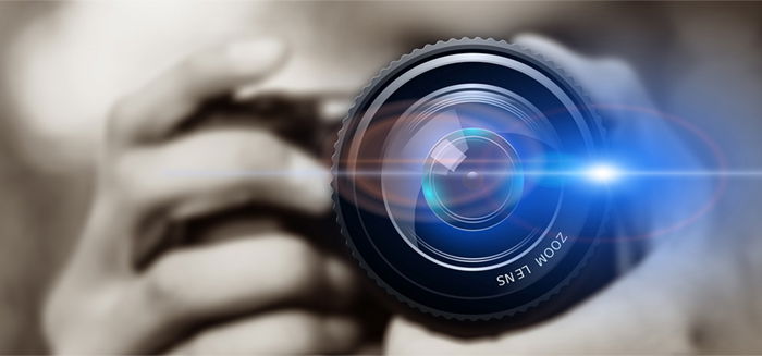 A person looking through a camera lens with selective focus lens flare