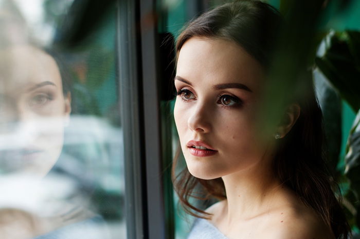 Portrait of a woman with her reflection in a window showing natural light photography