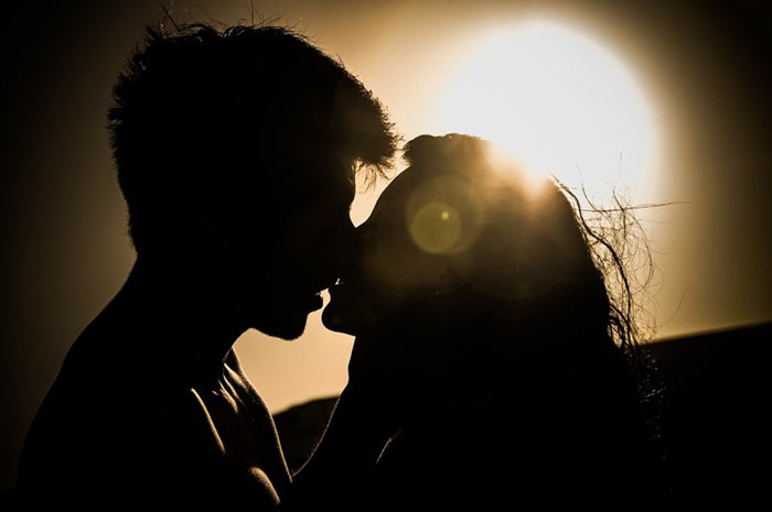 Silhouette of a couple kissing backlit by the sun as a light source