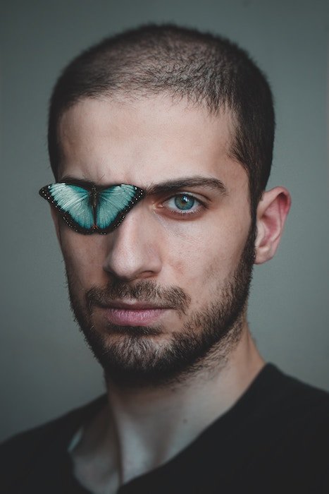 Portrait of a man with one eye covered with a butterfly