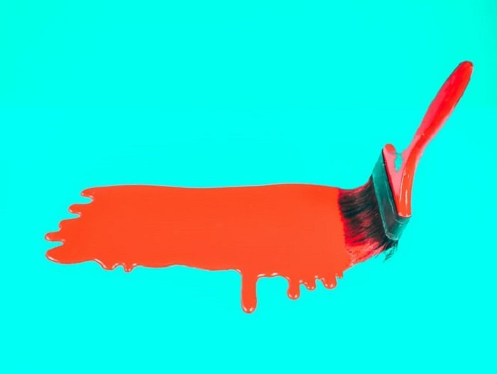 paint brush with red paint on a bright background