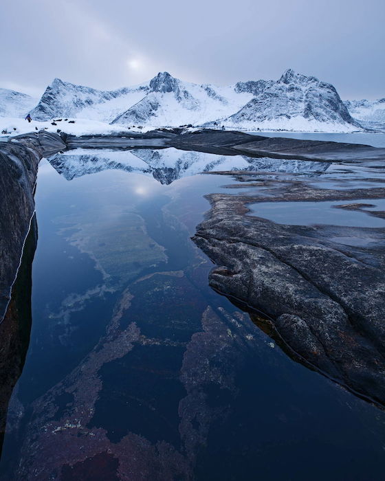 still water mirrors snowy mountains in the winter landscape