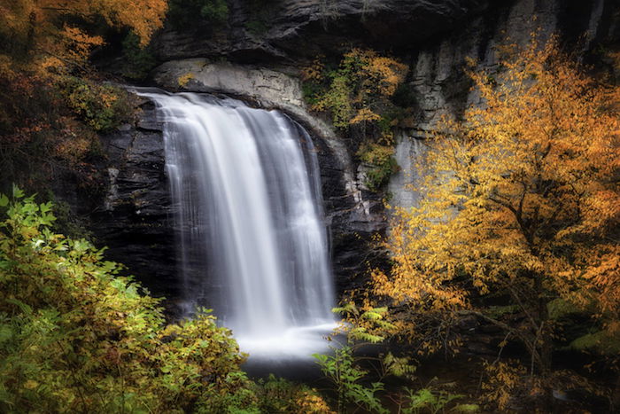 a long exposure shot of a waterfall in the autumn landscape