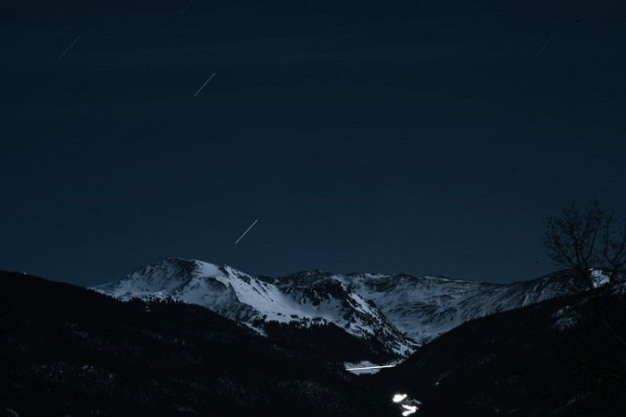 image of shooting stars on a dark mountainous landscape