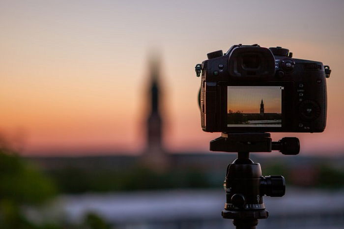 image of a camera on a tripod with a blurry sunset in the background