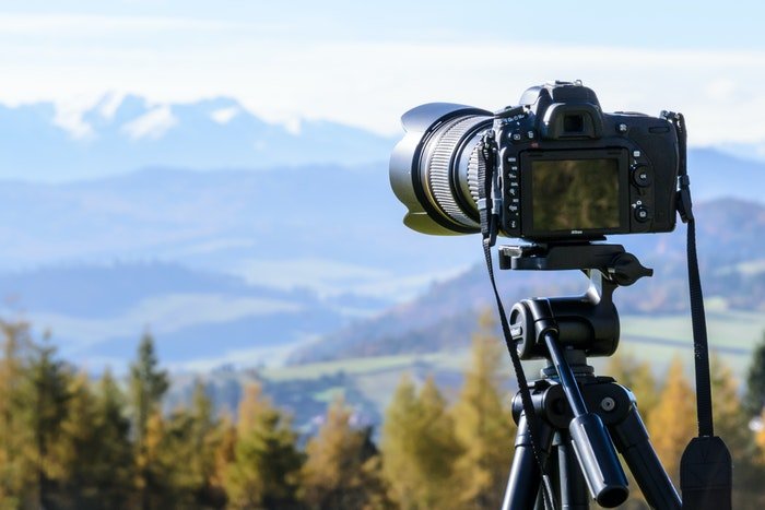 Camera set up on a tripod facing a mountainous landscape scene