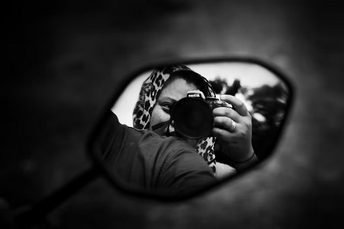 a black and white self portrait reflection taken in a car side mirror