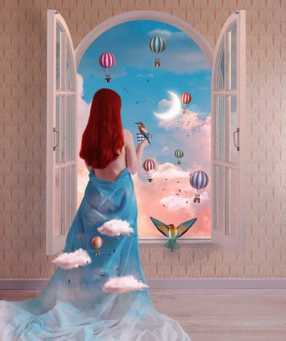 woman standing by a window looking out at clouds with miniature hot air balloons in the sky