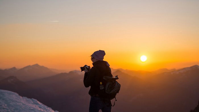 Photographer in a mountainous scene with a sunset in the background