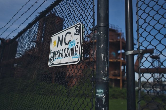 a no trespassing sign on a chain link fence at dawn