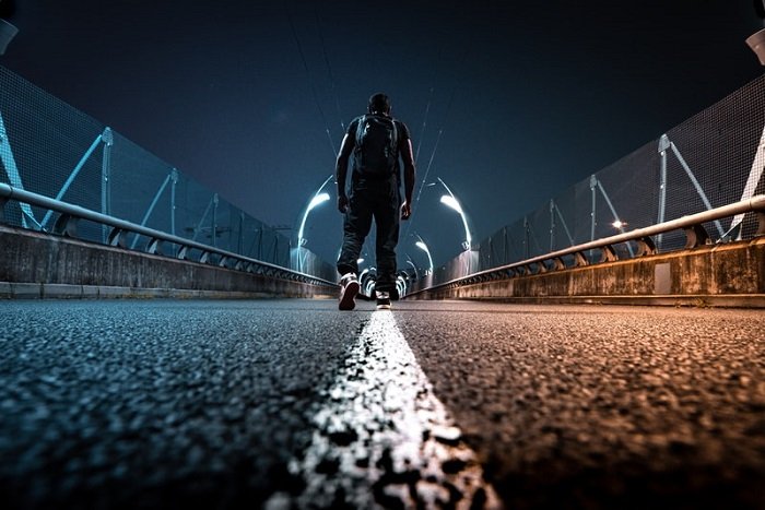 man walking down a road wearing a backpack in a stylised urban scene