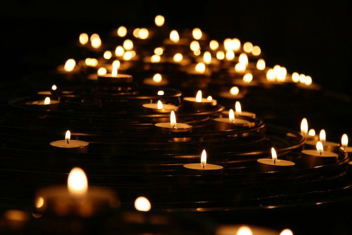 Multiple lit tea candles at night with center manual focus