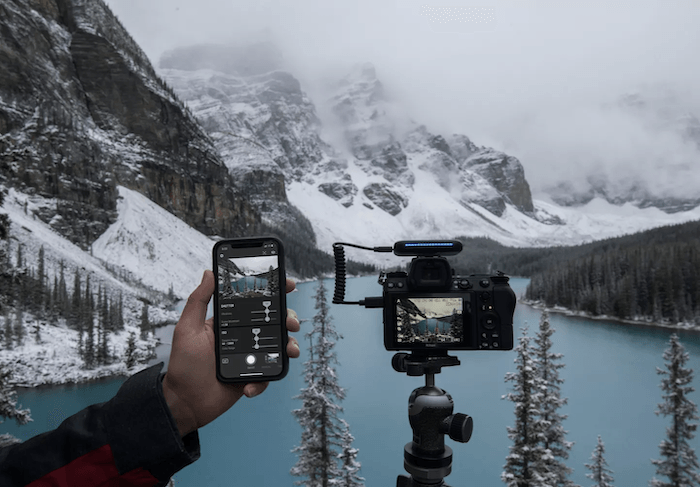 AI摄影:arsnal硬件相机设置与一个人手持智能手机控制与雪山景观背景