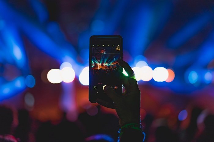 best camera app for android: a photo of someone using their smart phone to take a photo at a concert with lightship