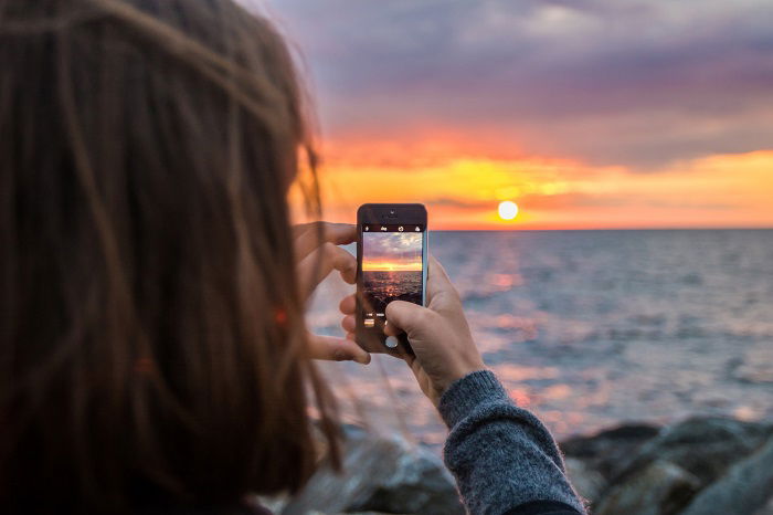 najlepsza aplikacja do aparatu na Androida: fotograf używa swojego smartfona, aby uchwycić piękny zachód słońca