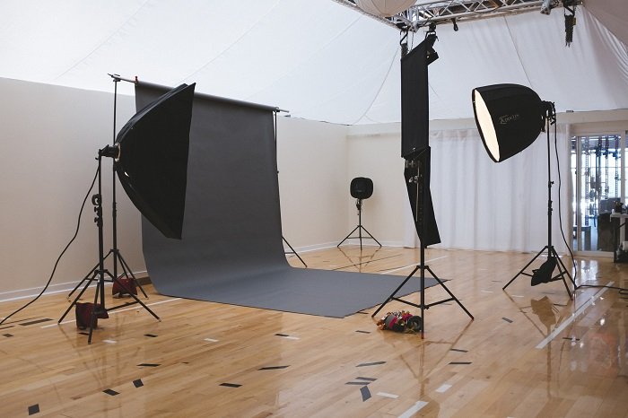 best photography backdrops: multiple umbrella lights pointed at a black backdrop in a photography studio