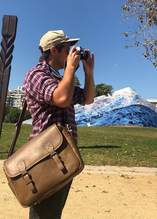 photographer taking a photo while wearing the Black Forest Messenger Camera Bag