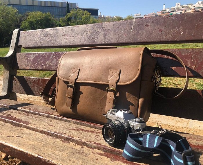 Black Forest leather camera bag posed on a bench with a camera