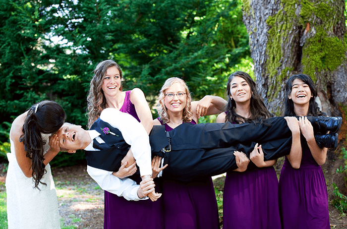 groomsmen photo idea: an image of several bridesmaids in purple carrying the groom