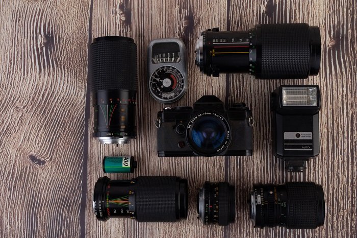 flat lay image of a camera with multiple lenses and flashes on a wooden table