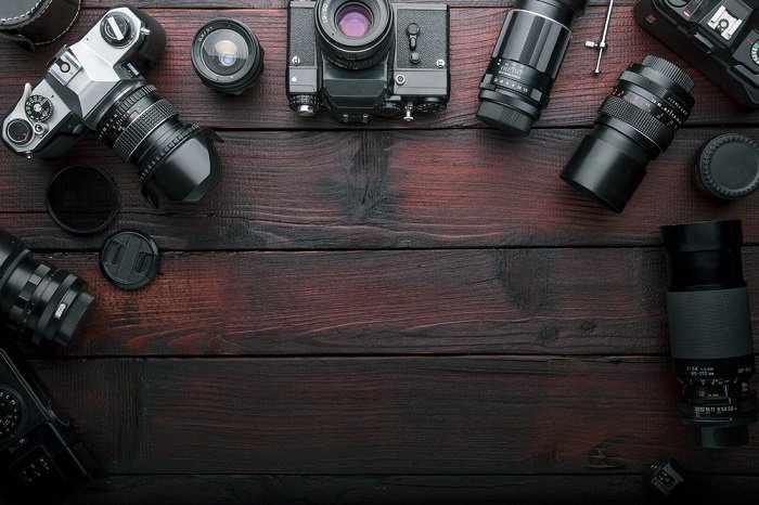 a flat lay photo of multiple camera on top of a wooden table